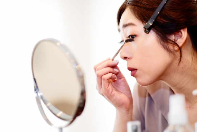 鏡の前でメイクを行う女性