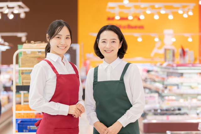 エプロンをして微笑んでいるパートの中年女性とアルバイトの若い女性