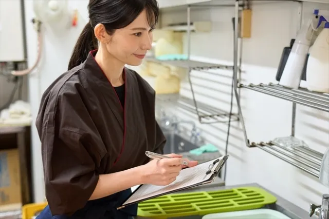 チェック表を確認しながら衛生管理に取り組む女性スタッフ