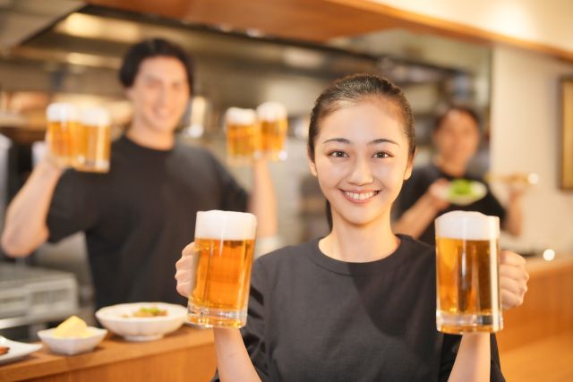 両手にビールをもってこちらに笑顔を向ける女性スタッフ