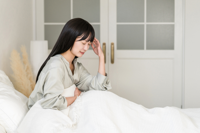 ベッドで頭痛に悩まされる女性