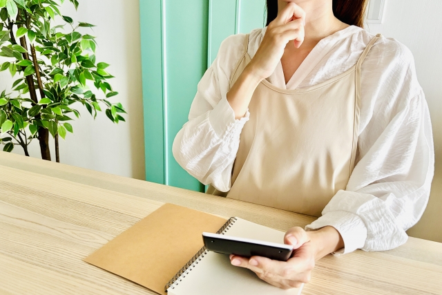 電卓と筆記用具を広げて考える女性の手元