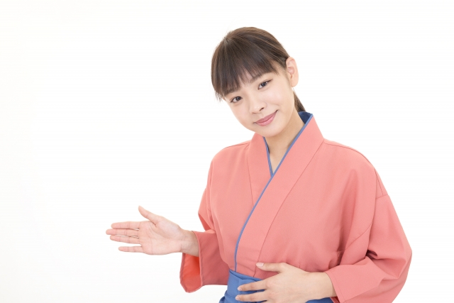 右手で進行方向を指し示す和風の制服を着た女性スタッフ