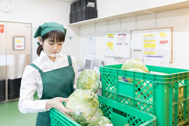 スーパーの裏で商品を確認する女性店員