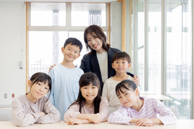 女性講師を囲むように集まる5人の子どもたち
