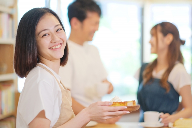 デザートをお客様のもとへ運ぶ若い女性店員
