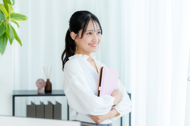 タブレットを手にオフィスに佇む笑顔の若い女性