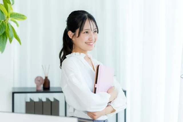 タブレットを手にオフィスに佇む笑顔の若い女性