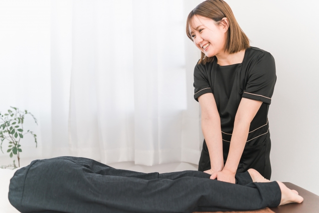 お客様の脚を笑顔でマッサージする女性スタッフ