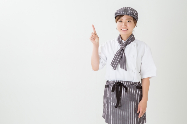 こちらに微笑みながら指を上に向けて指す女性スタッフ
