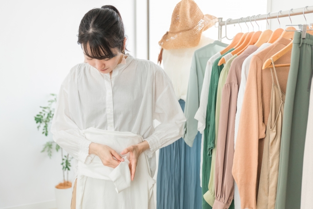 アパレル店で商品の服をたたむアルバイトの女性スタッフ