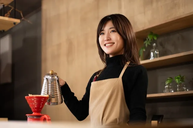 コーヒーを淹れるカフェの女性スタッフ