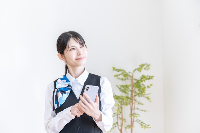 スマートフォンを操作しながら考えるスマホショップの女性販売員