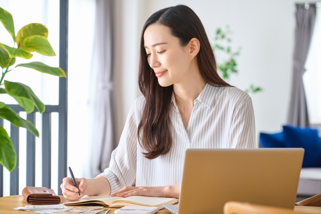 自宅で明細などを確認しながらメモを書く女性