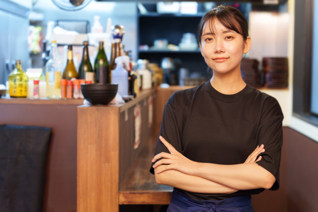 腕を組みながらこちらを見つめる居酒屋の女性スタッフ