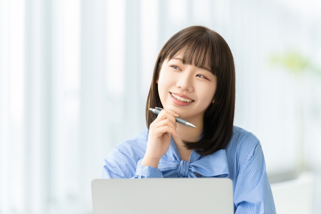 ペンを片手に微笑む女性