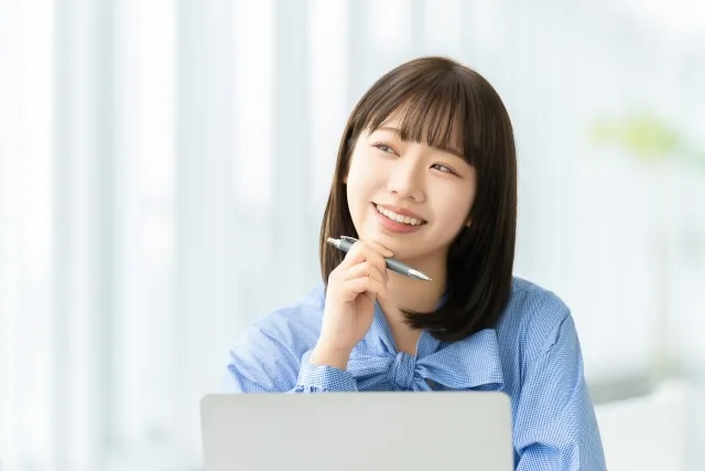 ペンを片手に微笑む女性