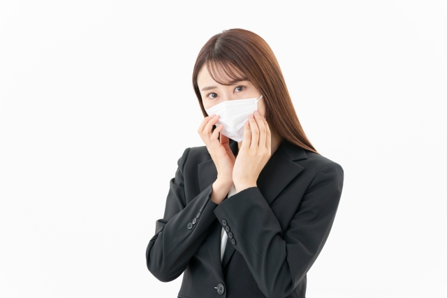 マスクをした女性が口元に手を当てて悩んでいる様子