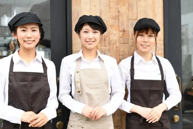 店の前に並んで立つ3人の女性カフェスタッフ