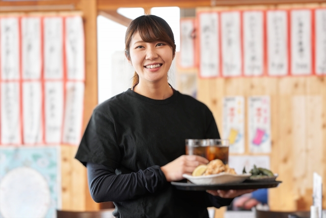 注文された料理やドリンクを届けに向かう居酒屋の女性スタッフ