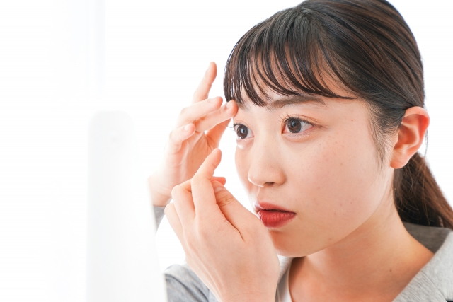 コンタクトをつけようとしているスーツ姿の女性