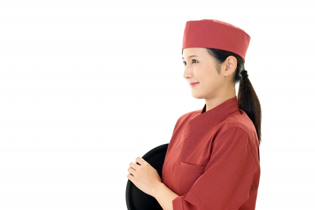 脇にトレーを抱えて横を向いている制服姿の女性スタッフ