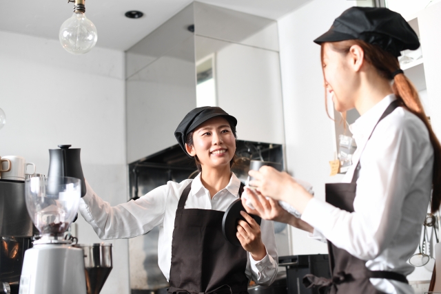 コーヒーマシンの使い方を教える女性店員とメモを取る後輩の女性店員