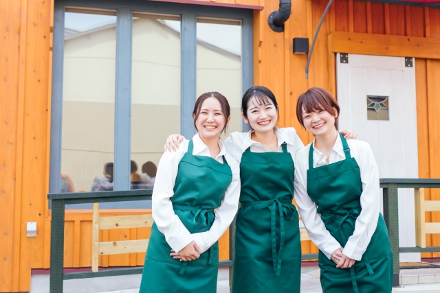 お店の前で肩を組む3人の女性スタッフ