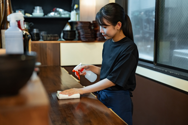 お店のカウンターを拭いている女性店員