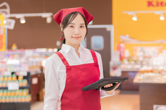 スーパーでタブレットを持ちながら業務を行う女性スタッフ