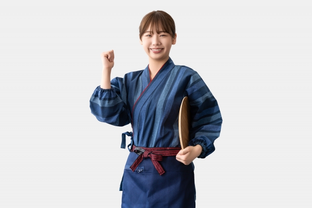 トレーをわきに抱え、ガッツポーズをする女性スタッフ