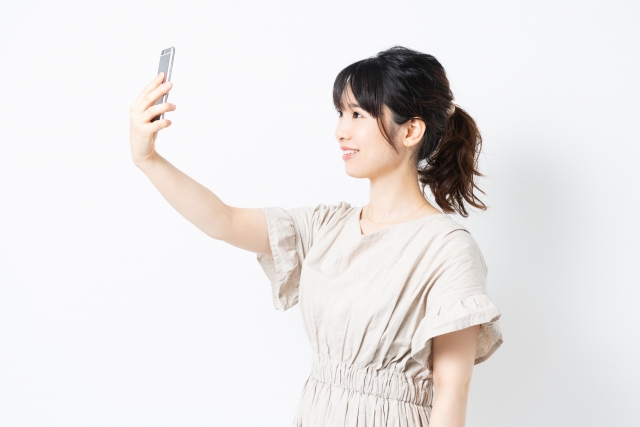 スマホで自撮りを行うポニーテールの女性