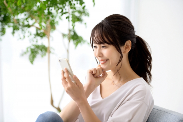 スマホの画面を見つめ微笑む女性