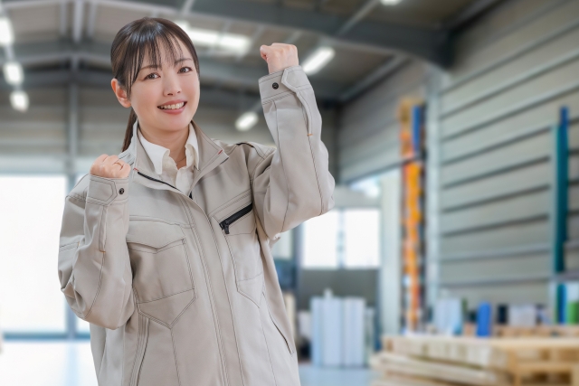 倉庫とガッツポーズする作業員女性