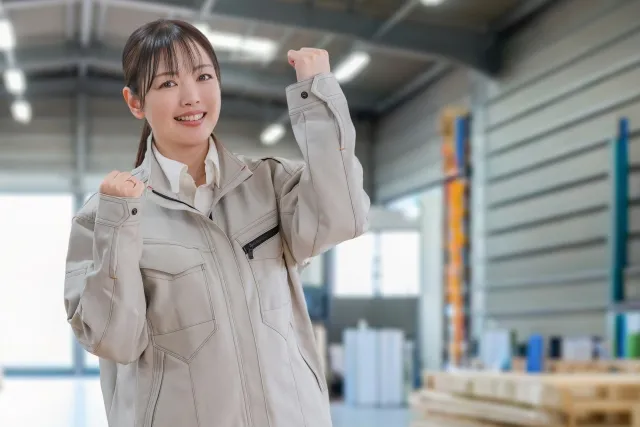 倉庫とガッツポーズする作業員女性