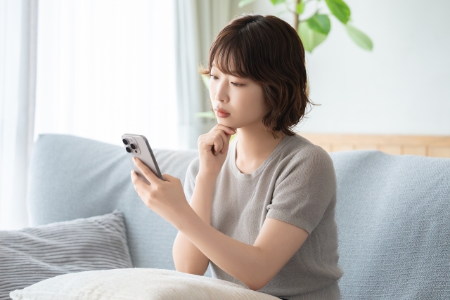 スマホを見ながら考え込むショートカットの女性
