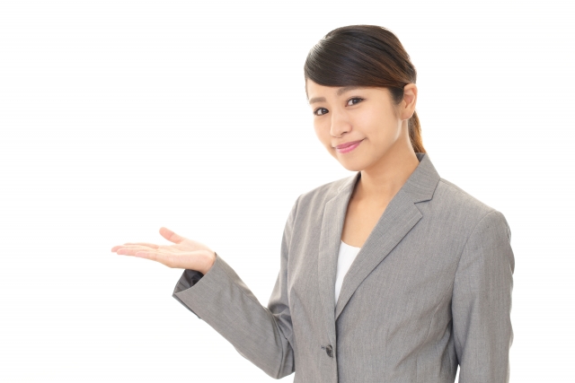 グレーのスーツに身を包み、右手で進行方向を示す女性スタッフ