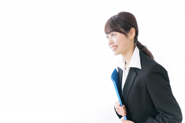 バインダーを脇に抱えながらお客様に会釈する女性スタッフ