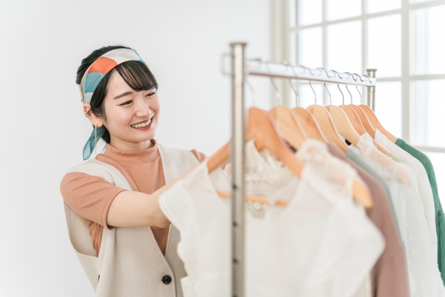 お店に陳列されている洋服をチェックする笑顔の女性スタッフ