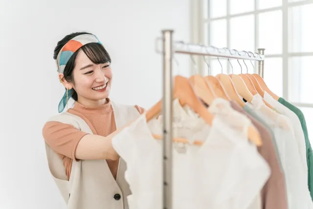 お店に陳列されている洋服をチェックする笑顔の女性スタッフ