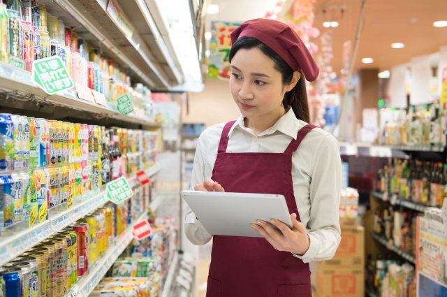 スーパーに陳列された商品の在庫管理を行う女性スタッフ